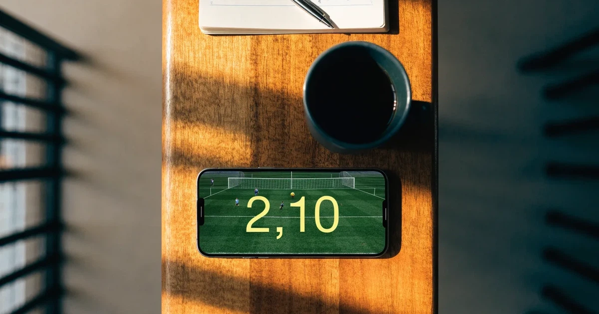 Ein Smartphone mit dunklem Bildschirm liegt auf einem Tisch in einem Café, daneben eine Tasse und ein Notizbuch.